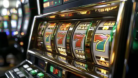 Close-up of a slot machine showing winning sevens on the reels