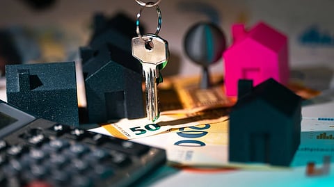House keys and model homes on banknotes symbolize real estate investment