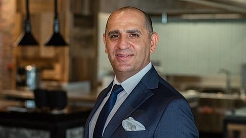 Marvin Alballi in a navy suit standing in a modern restaurant interior