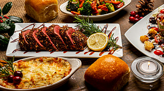 Elegant Thanksgiving dinner with sliced roast, vegetables, and bread rolls