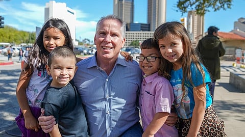 Thomas J. Henry smiling with a group of children outdoors