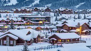 Snowy village with chalets and mountains during winter evening