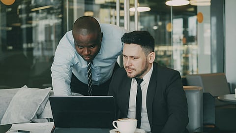 Two professionals review information on a laptop in an office