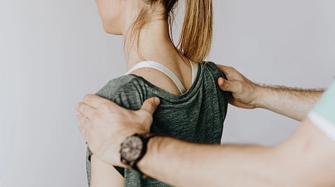 Chiropractor adjusting a patient’s upper back during a session