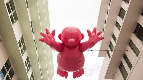 Pink inflatable figure suspended between two buildings on Lincoln Road