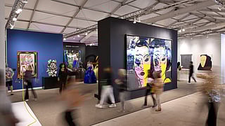 People viewing contemporary art inside a bustling Miami Art Week exhibition tent