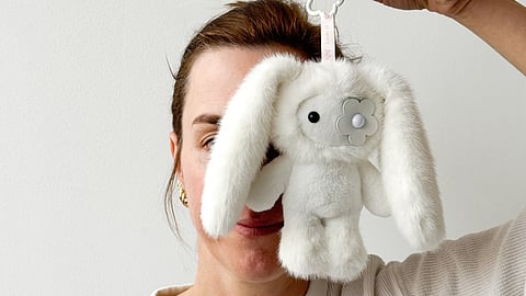 Cj Hendry holding a white juju plush toy in front of her face