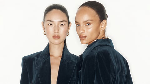 Two models in dark velvet jackets posing against a white background