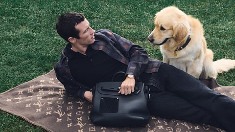 Man lounging with dog on Louis Vuitton blanket and pet bag