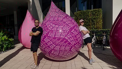Artists pose beside large pink elf-inspired sculptures at W South Beach installation