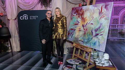 J Balvin and Sophie Tea posing next to a finished painting at the event
