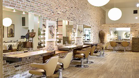 Le Bazaar styling area with mirrors, brick walls, and tan salon chairs