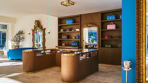 Boutique interior with wood shelving, colorful bags, and gold accents at Christopher King