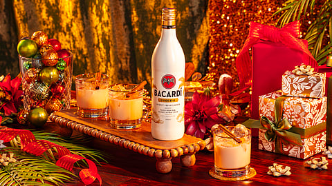 Bacardí coquito bottle with holiday cocktails, ornaments, and wrapped gifts on a decorated table