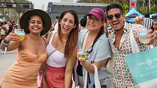 Smiling guests holding drinks at the Visit Lauderdale Food & Wine Festival outdoors