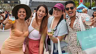 Smiling guests holding drinks at the Visit Lauderdale Food & Wine Festival outdoors