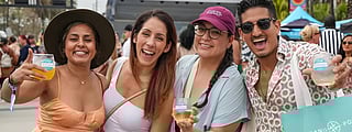 Smiling guests holding drinks at the Visit Lauderdale Food & Wine Festival outdoors
