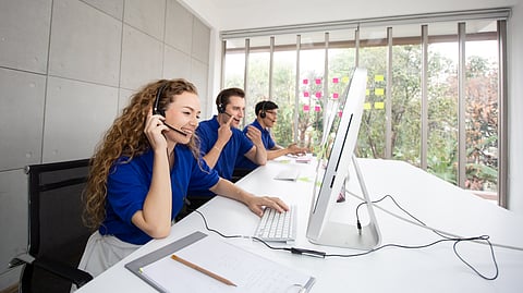 Customer support team wearing headsets working at desktop computers