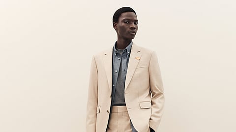 Model wearing Louis Vuitton Trunk Edition beige suit with layered shirt styling