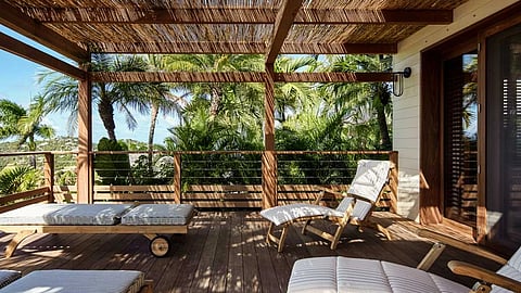 St. Barts villa terrace with lounge chairs, pergola, and tropical palm views