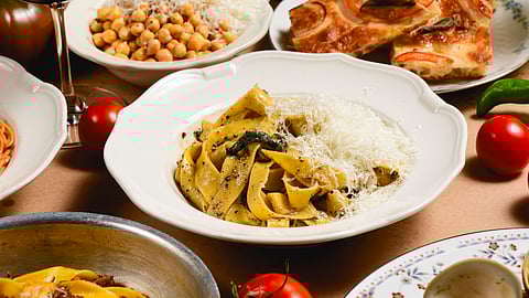 Bowl of handmade black pepper pasta surrounded by Italian dishes at Bella restaurant