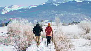 Residents snowshoe along a winter trail at Tributary with the Teton Range in the background