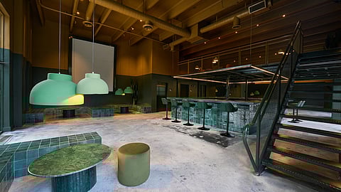 Cafeina interior with green tile bar, sculptural lighting, and mezzanine staircase in Wynwood