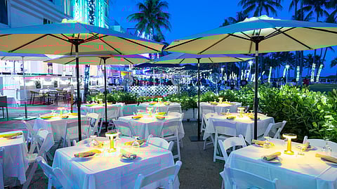 Evening outdoor dining with white tablecloths and palm trees along Ocean Drive