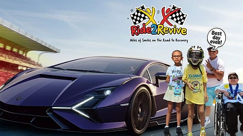 Ride2Revive children smiling beside a supercar at a racetrack during a charity healing event