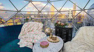 Interior of a heated rooftop igloo at Somewhere Nowhere with plush seating and sweeping NYC views