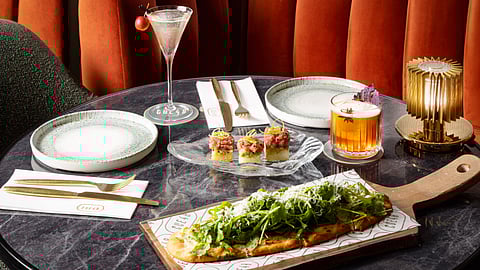 Flatbread, tuna tartare bites, and cocktails on a table at Cue 48 in Times Square