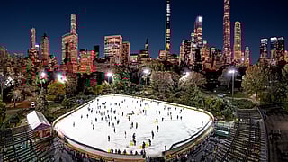 Aerial night view of Wollman Rink in Central Park with the NYC skyline glowing behind