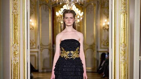 Runway model wearing a black strapless couture dress with gold embroidery by Elephant Princess