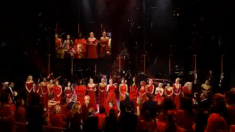 Performers and guests in red gather onstage at the Red Dress Collection® Concert in NYC