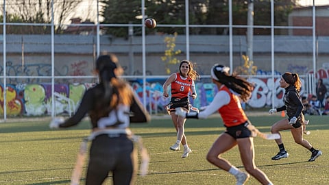 Girls competing in a flag football game during a fast-paced play
