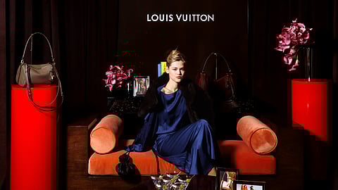 Model poses beneath the Louis Vuitton logo with Express bags displayed at the Manhattan launch event