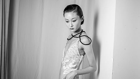 Model in lace trimmed satin slip with beaded shoulder detail backstage in black and white