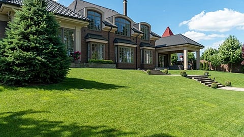 Luxury estate with landscaped grounds and expansive green lawn under a clear sky