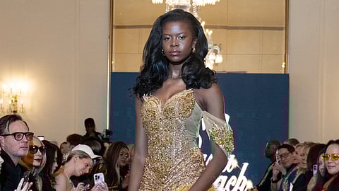 Model in gold sequined gown with yellow feather trim walks runway at NYFW presentation