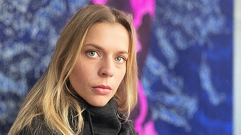 French artist Tess Dumon poses before one of her luminous gouache paintings