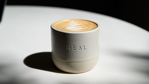 Ceramic cup of latte with HEAL branding served at HEAL Café in Midtown Miami
