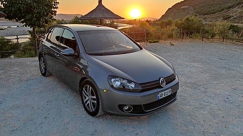 Gray Volkswagen parked at sunset along Albania’s coastal landscape