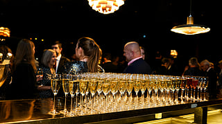 Rows of champagne flutes set on a bar during an elegant awards night cocktail reception
