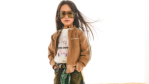 Child model wearing Palm Angels kidswear in desert setting with oversized denim and jacket