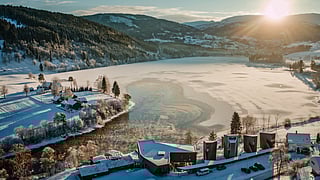 Snow-covered Norwegian landscape with frozen lake and modern cabins at sunrise