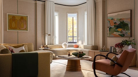 Living room with curved sofa, armchairs, artwork and large windows with soft natural light