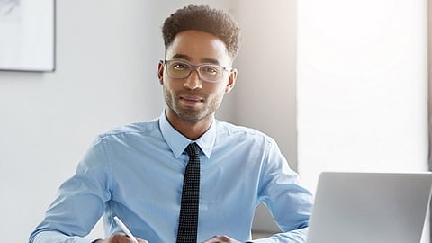 Business professional working at a laptop while reviewing notes in a modern office setting