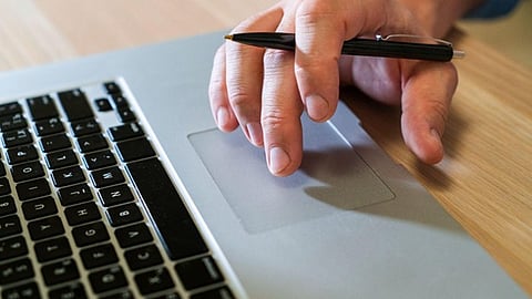 Person using laptop trackpad with pen, symbolizing digital resource management and automation