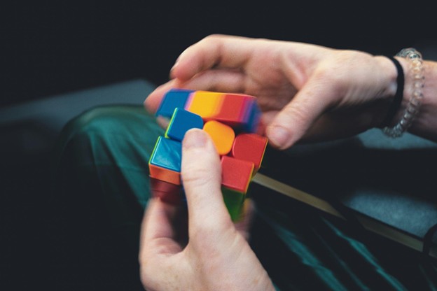 Hands twisting puzzle cube, symbolizing cognitive training and mental exercises