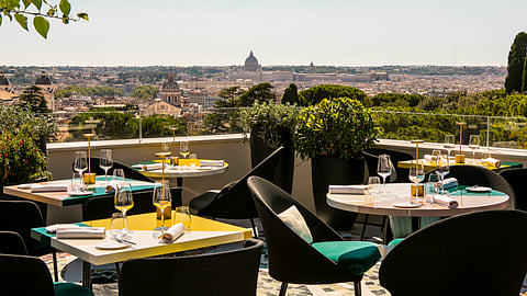 Rooftop dining terrace with tables set against Rome skyline and St. Peter’s Basilica